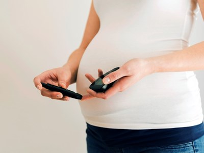 En gravis kvinne som måler blodsukkeret med blodsukkermåler