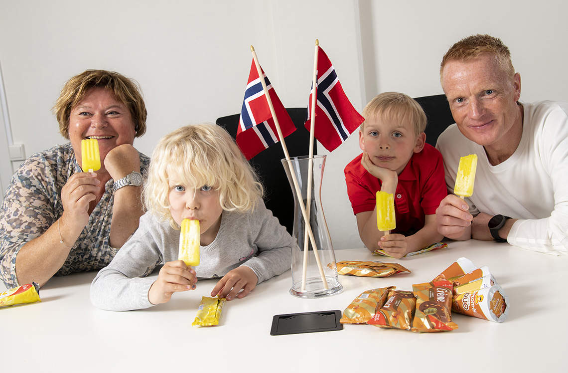 To voksne og to barn tester is i et rom med norske flagg